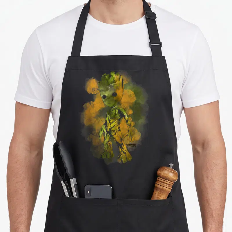 Guardian nebula apron - Groot watercolor illustration with green yellow orange smoke and Guardians of the Galaxy Vol 2 — shown on a black cotton canvas apron against a white background