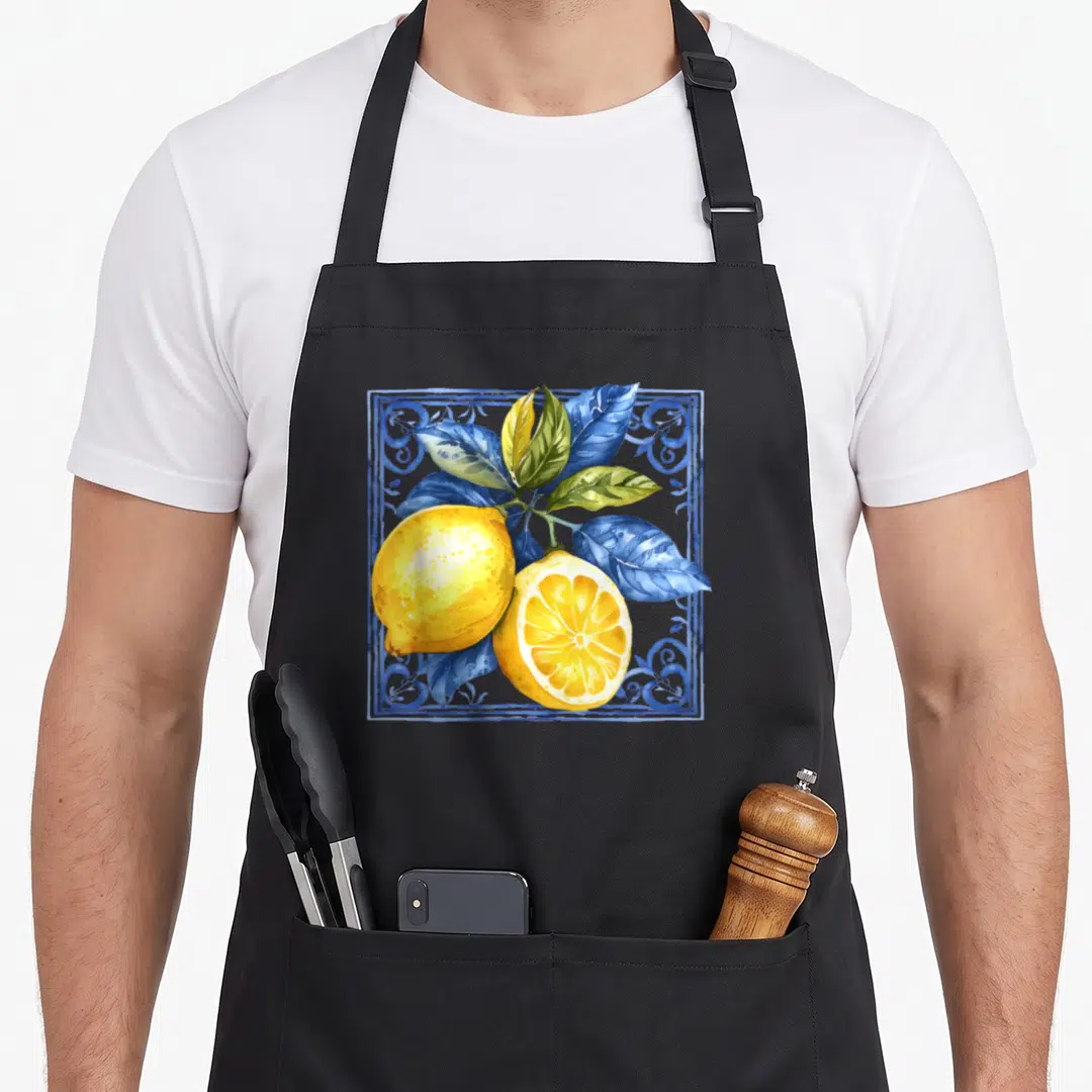 Blue lemon apron - Two yellow lemons and blue leaves in a decorative watercolor square border — shown on a black cotton canvas apron against a white background