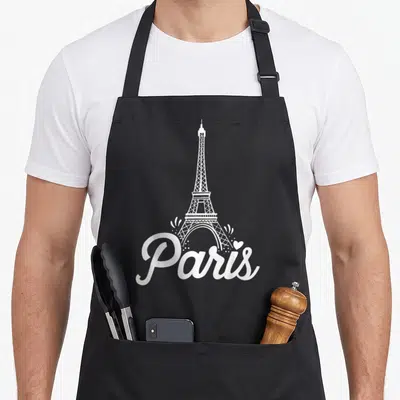 France eiffel paris apron - White minimalist Eiffel Tower illustration above Paris script with heart and sparkles — shown on a black cotton canvas apron against a white background