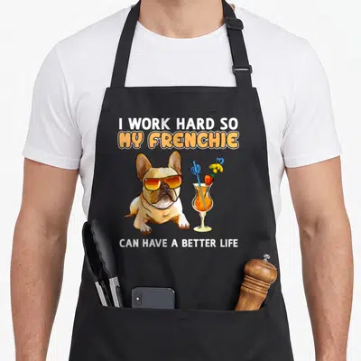 Frenchie bulldog french apron - Cartoon tan Frenchie with orange sunglasses next to an orange cocktail glass — shown on a black cotton canvas apron against a white background