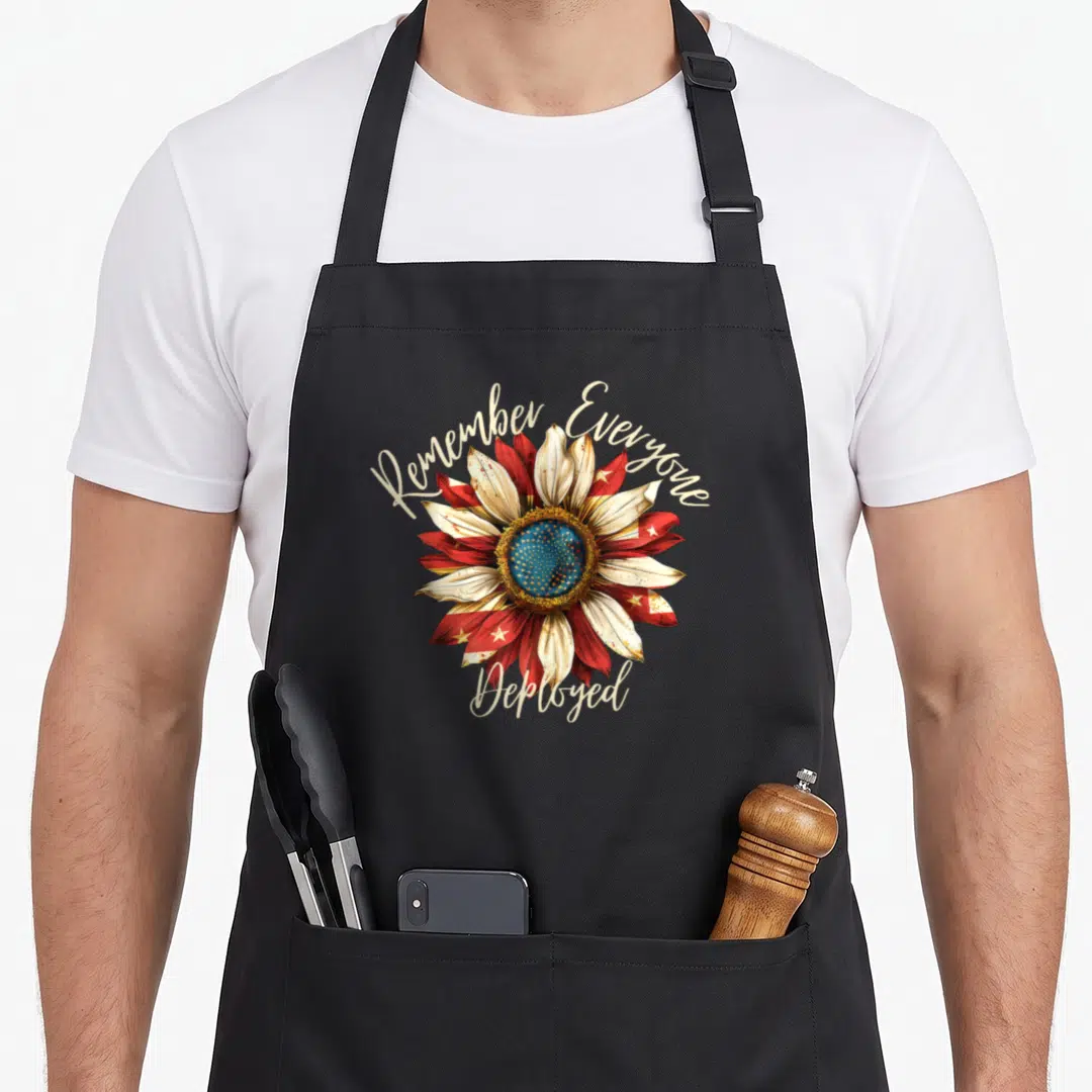Remember patriotic apron - Red white blue sunflower with Remember Everyone Deployed script text — shown on a black cotton canvas apron against a white background