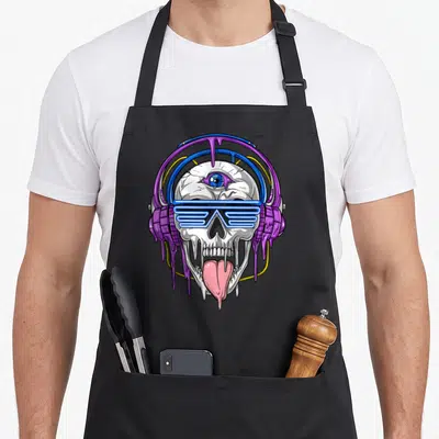 Psytrance skull apron - Cartoon skull wearing blue shutter shades and purple headphones with pink tongue and dripping — shown on a black cotton canvas apron against a white background