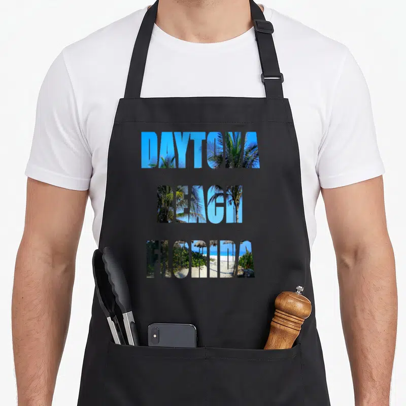 Daytona beach florida apron - Stacked text DAYTONA BEACH FLORIDA filled with beach photo and palm trees — shown on a black cotton canvas apron against a white background