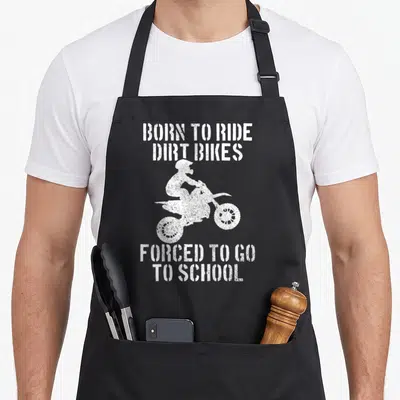 School bike apron - White distressed dirt bike rider silhouette between Born To Ride and Forced To Go To School text — shown on a black cotton canvas apron against a white background