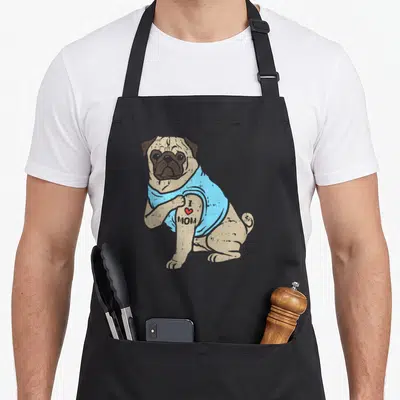 Pug animal dog apron - Sitting tan pug in blue shirt showing I heart MOM tattoo on arm — shown on a black cotton canvas apron against a white background