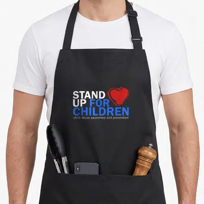 Stand child abuse prevention apron - Stacked STAND UP FOR CHILDREN text with overlapping red heart on left side — shown on a black cotton canvas apron against a white background