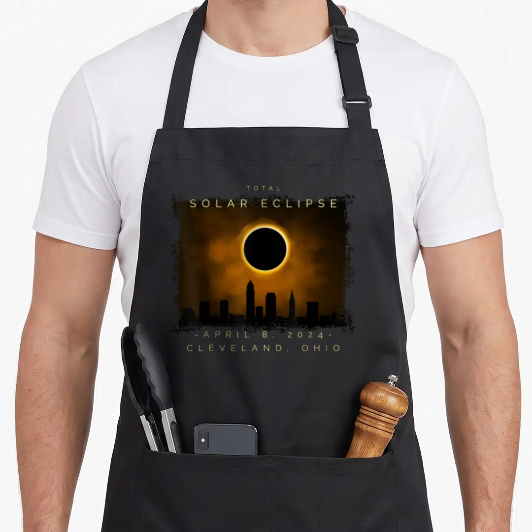 Total cleveland apron - Gold text Total Solar Eclipse over black skyline silhouette and orange corona inside distressed — shown on a black cotton canvas apron against a white background