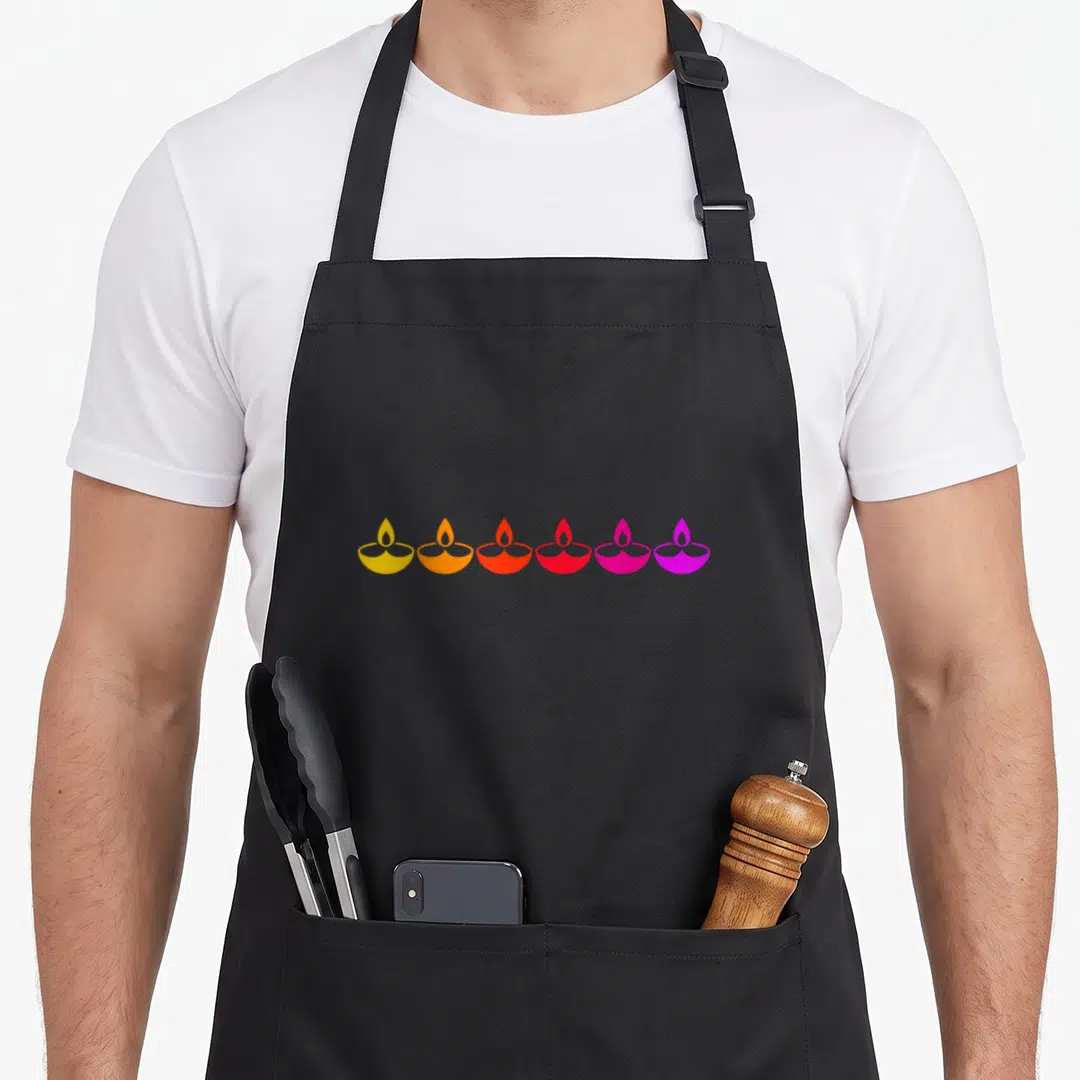 Diwali colorful aprons - Six minimalist diya lamps in a horizontal row transitioning from yellow to purple — shown on a black cotton canvas apron against a white background