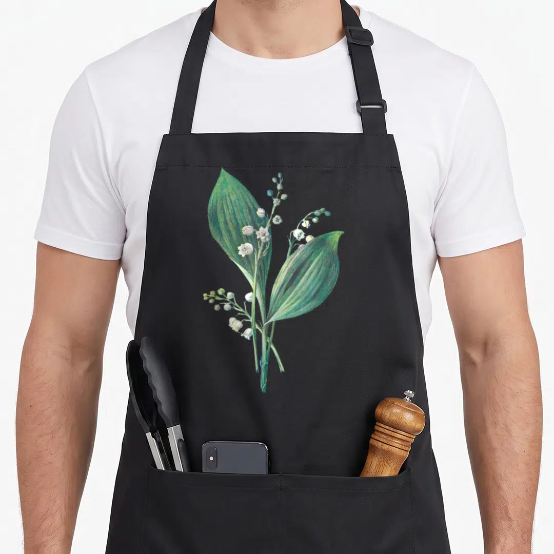 Valley white lily apron - Botanical drawing of Lily of the Valley with green leaves and white bell flowers on stems — shown on a black cotton canvas apron against a white background