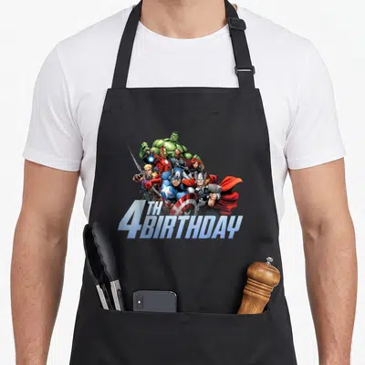 Action shot birthday apron - Avengers group in blue red green silver with TH 4BIRTHDAY 3D text overlay — shown on a black cotton canvas apron against a white background