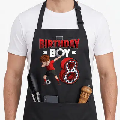 Player 8th birthday apron - Dabbing soccer boy, number 8 with ball pattern, BIRTHDAY BOY text in red and white — shown on a black cotton canvas apron against a white background