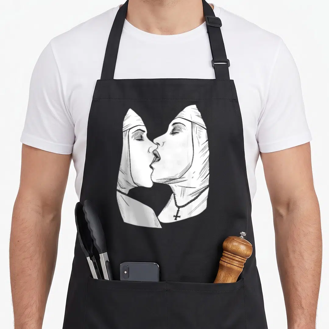 Hot nun apron - Two nuns in profile kissing, white line art, rosary cross — shown on a black cotton canvas apron against a white background