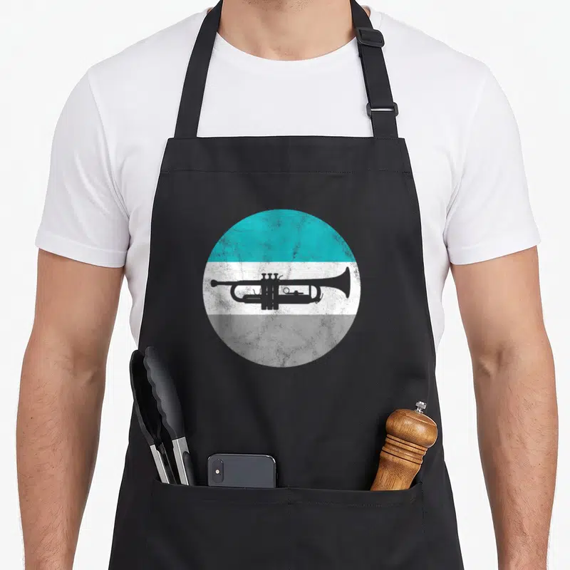 Cute trumpet apron - Grey trumpet silhouette on circle with teal white and grey horizontal bands — shown on a black cotton canvas apron against a white background