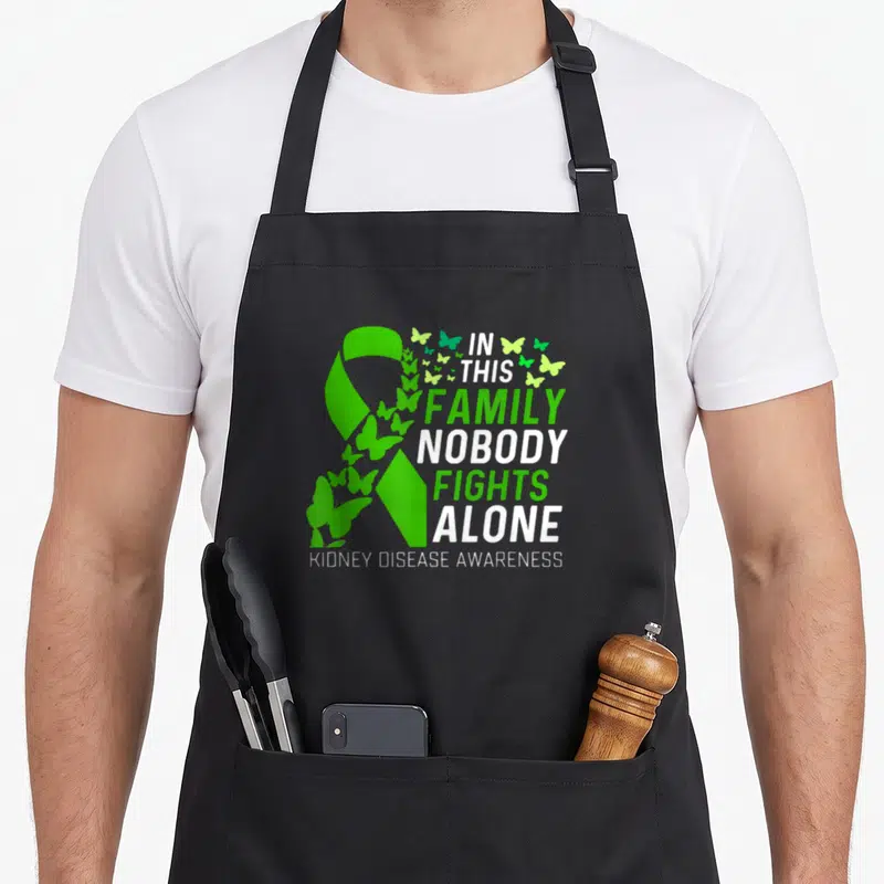 Fighting family aprons - Green ribbon with white text and flying butterflies for kidney disease awareness — shown on a black cotton canvas apron against a white background