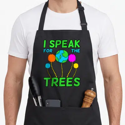 Planet tree apron - I SPEAK FOR THE TREES text around cartoon earth and four colorful fluffy trees — shown on a black cotton canvas apron against a white background