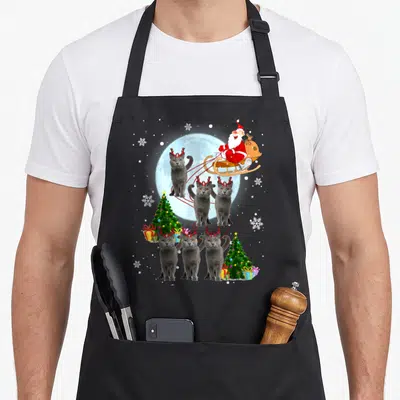 Reindeer russian aprons - Six grey cats with red antlers pulling Santa sleigh near green Christmas trees and gifts — shown on a black cotton canvas apron against a white background