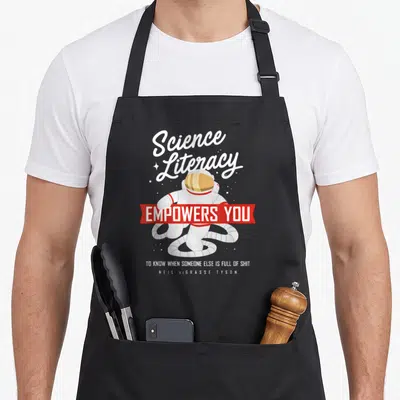 Neil degrasse science apron - Astronaut with Science Literacy quote and red banner on white background — shown on a black cotton canvas apron against a white background
