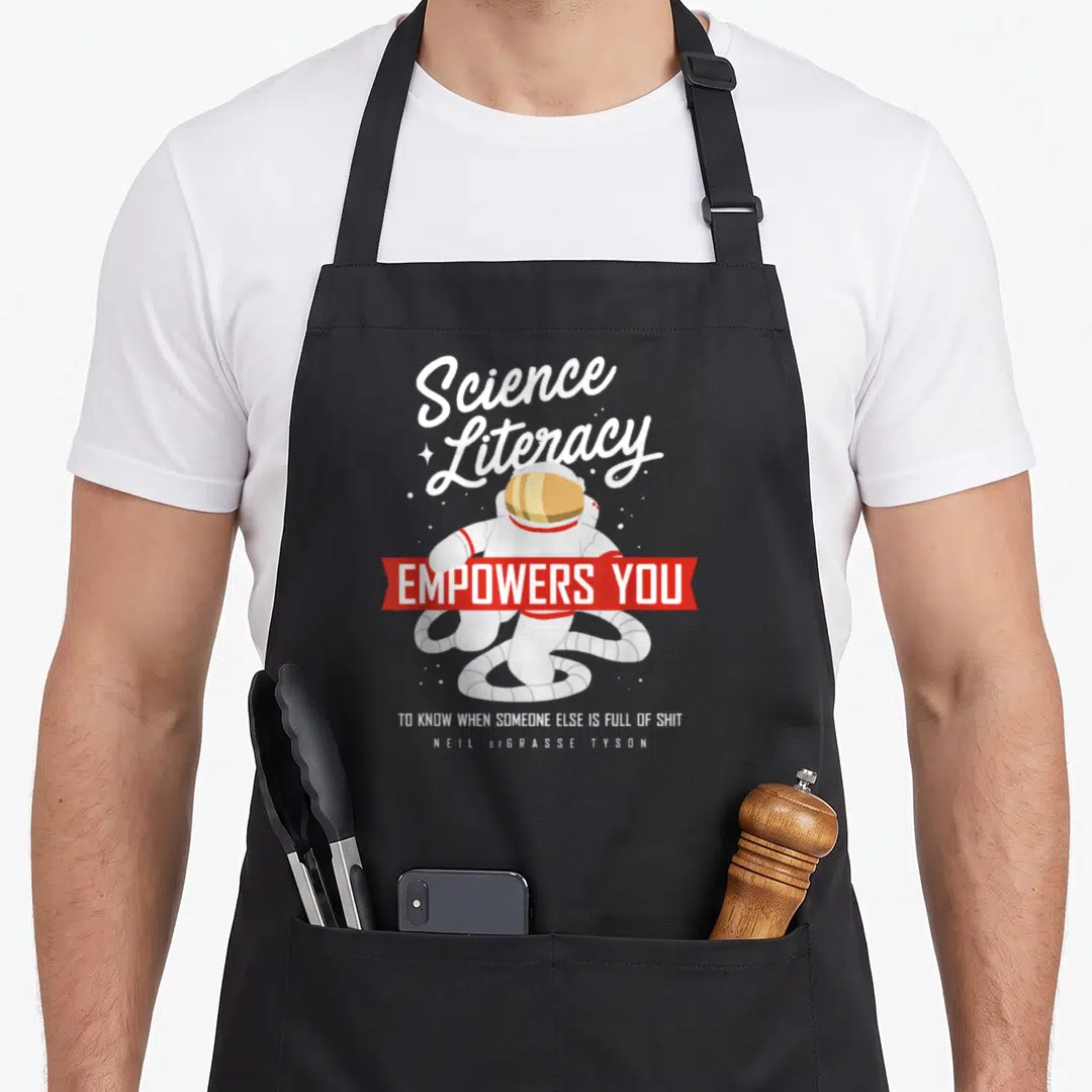 Neil degrasse science apron - Astronaut with Science Literacy quote and red banner on white background — shown on a black cotton canvas apron against a white background