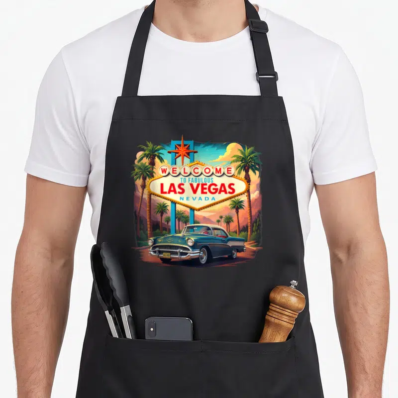 Vacation las vegas apron - Retro illustration of Welcome to Fabulous Las Vegas sign with vintage car and palm trees — shown on a black cotton canvas apron against a white background