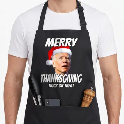 Joe thanksgiving apron - Joe Biden wearing a red Santa hat with white text reading Merry Thanksgiving Trick Or Treat — shown on a black cotton canvas apron against a white background