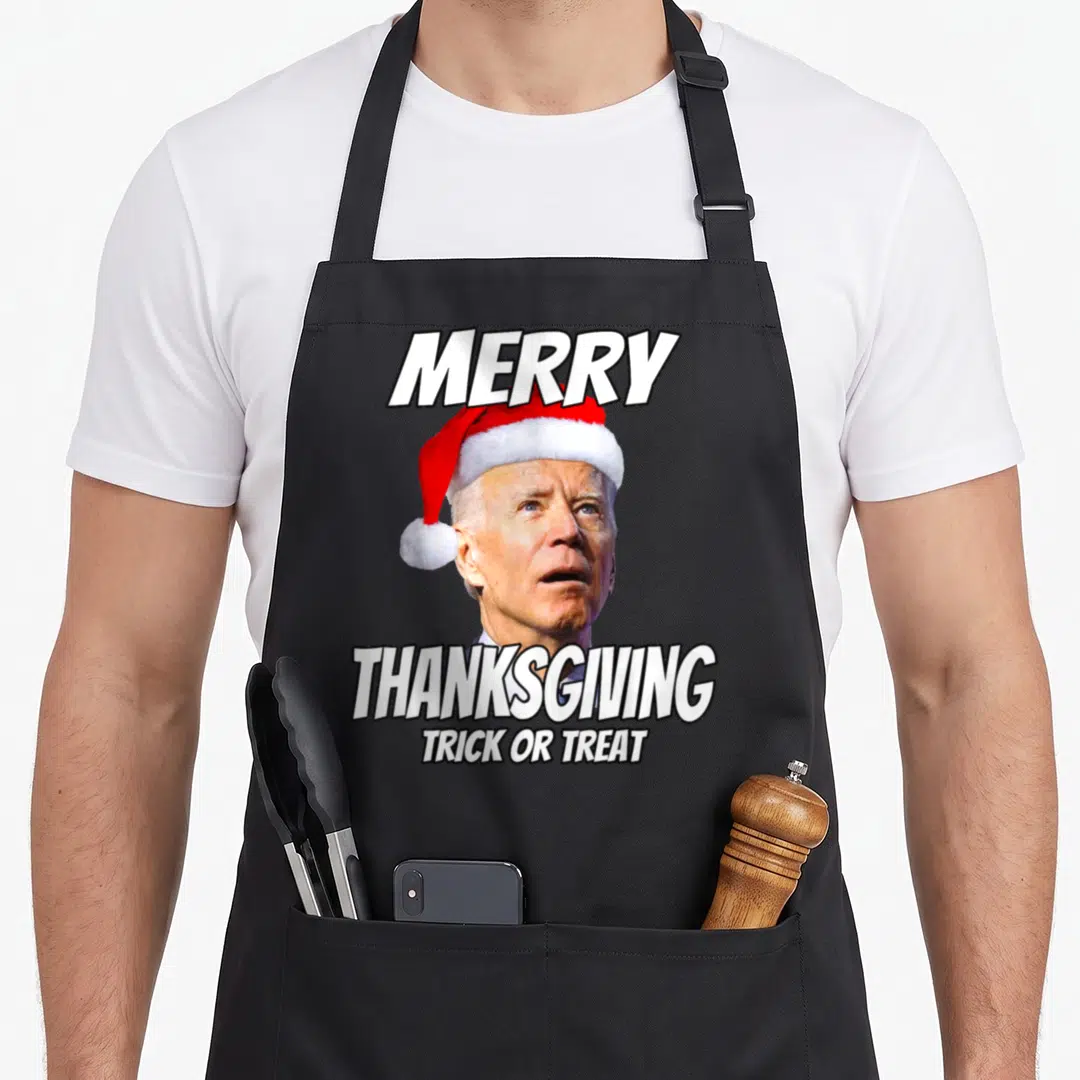 Joe thanksgiving apron - Joe Biden wearing a red Santa hat with white text reading Merry Thanksgiving Trick Or Treat — shown on a black cotton canvas apron against a white background