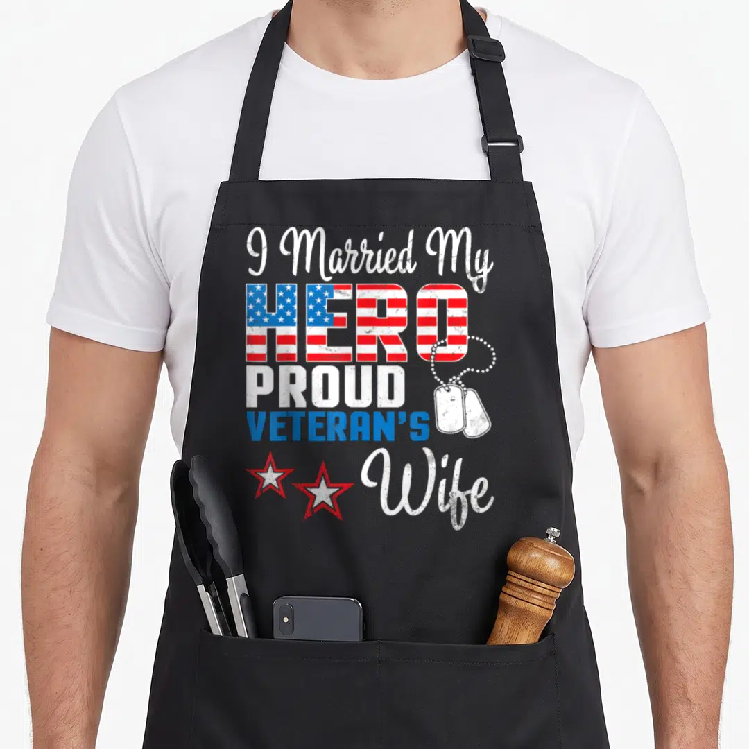 Married best husband apron - Stacked text I Married My Hero Proud Veteran's Wife with flag HERO, dog tags, two stars — shown on a black cotton canvas apron against a white background