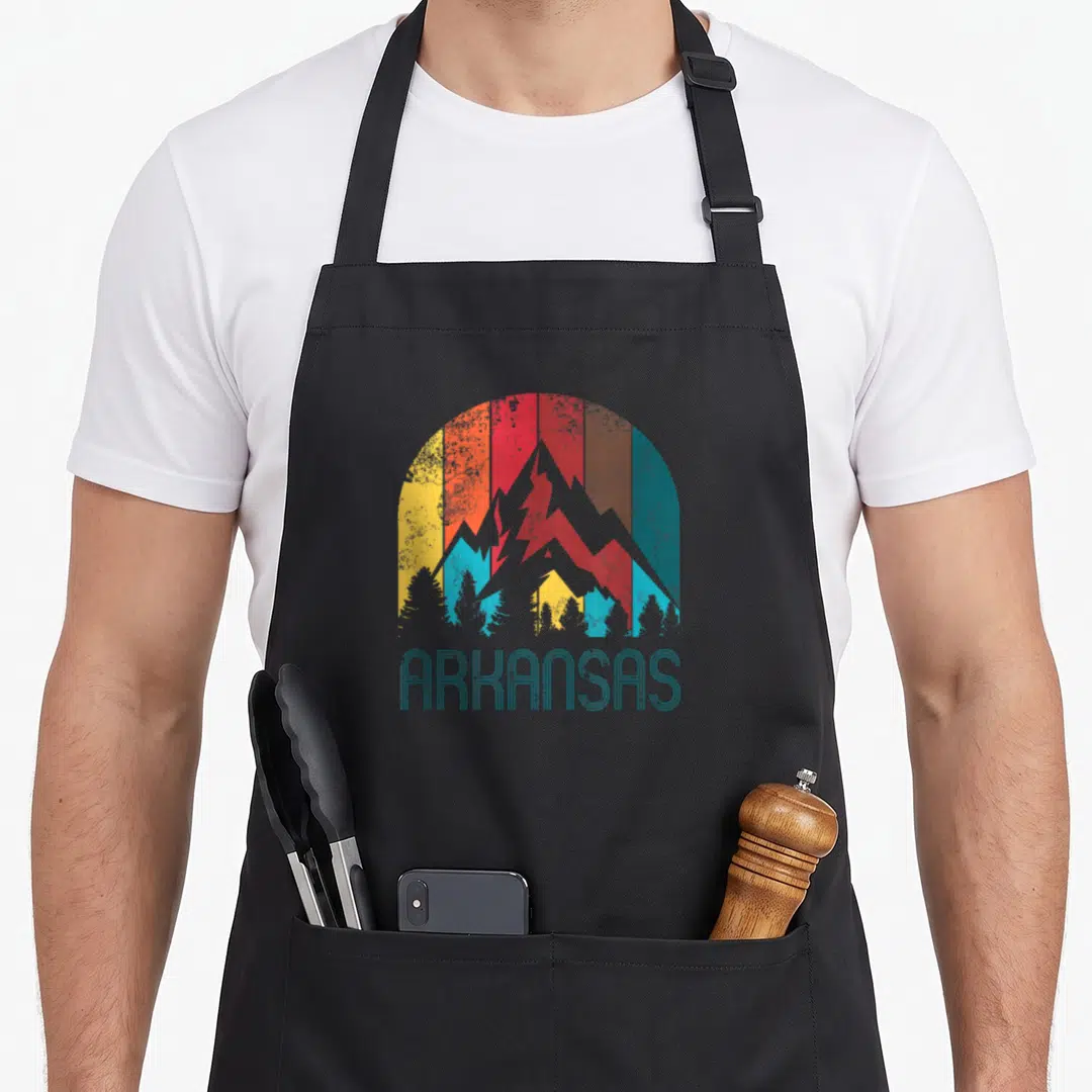 Funny arkansas apron - Retro grey mountains with teal red yellow stripes and ARKANSAS text — shown on a black cotton canvas apron against a white background