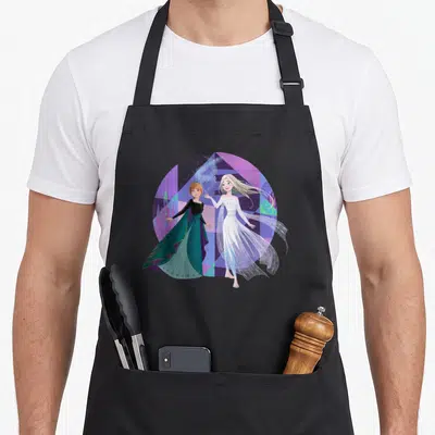 Queen frozen apron - Anna and Elsa in circular geometric background with magic swirls — shown on a black cotton canvas apron against a white background