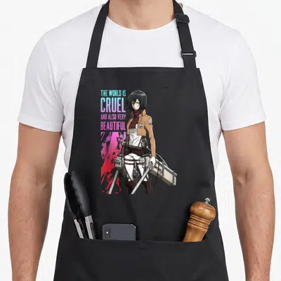 Cruel anime apron - Stacked teal and pink text beside a character in brown uniform holding gear over a red splash — shown on a black cotton canvas apron against a white background