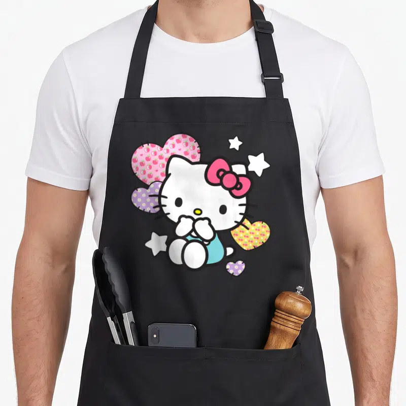 Star cherry apron - Hello Kitty with patched hearts containing apple, flower, and cherry patterns and white stars — shown on a black cotton canvas apron against a white background