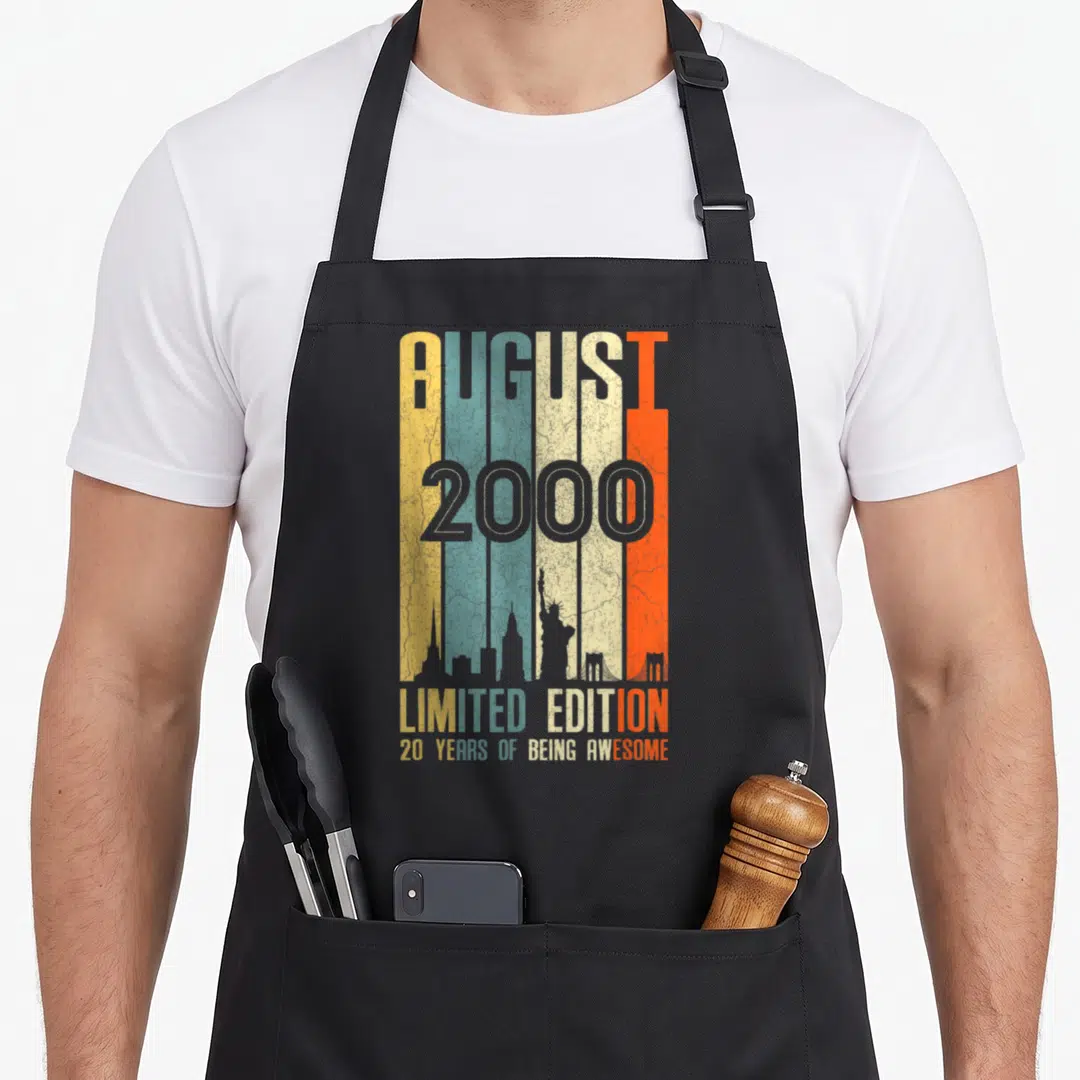 Vintage august birthday apron - Retro vertical stripes tan blue orange grey with grey NYC skyline silhouette and text — shown on a black cotton canvas apron against a white background