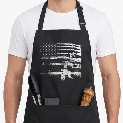 Gun machine apron - White distressed rifle silhouettes forming USA flag stripes on grey background — shown on a black cotton canvas apron against a white background