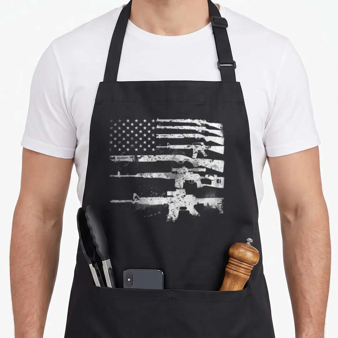 Gun machine apron - White distressed rifle silhouettes forming USA flag stripes on grey background — shown on a black cotton canvas apron against a white background