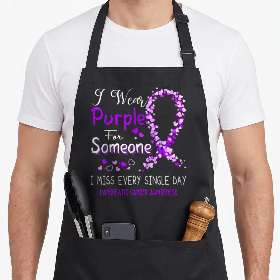 Someone walking apron - Purple heart ribbon and I Wear Purple For Someone text on white background — shown on a black cotton canvas apron against a white background