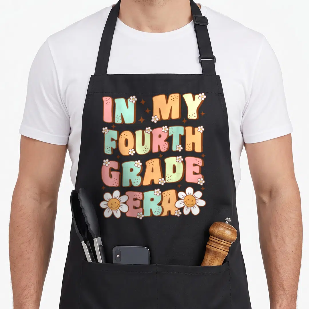 Fourth grade era apron - Stacked retro text IN MY FOURTH GRADE ERA with pink orange yellow green blue colors and white — shown on a black cotton canvas apron against a white background