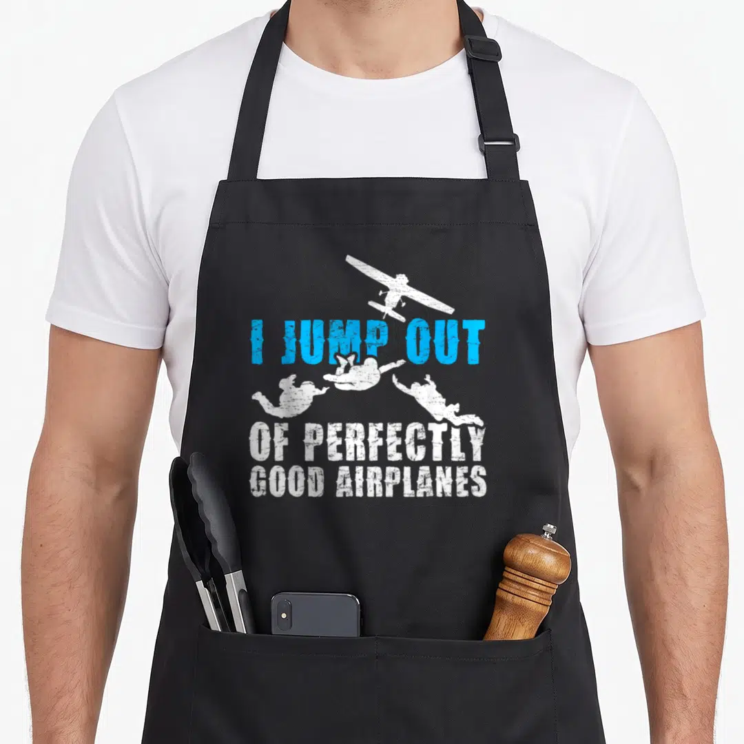Skydive skydiving apron - I JUMP OUT OF PERFECTLY GOOD AIRPLANES text with plane and three falling figures in blue — shown on a black cotton canvas apron against a white background