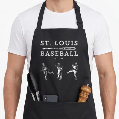 Louis baseball apron - White distressed text ST LOUIS BASEBALL EST 1882 with bat and three vintage player silhouettes — shown on a black cotton canvas apron against a white background