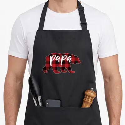 Papa buffalo apron - Red and black plaid bear silhouette with white papa text — shown on a black cotton canvas apron against a white background