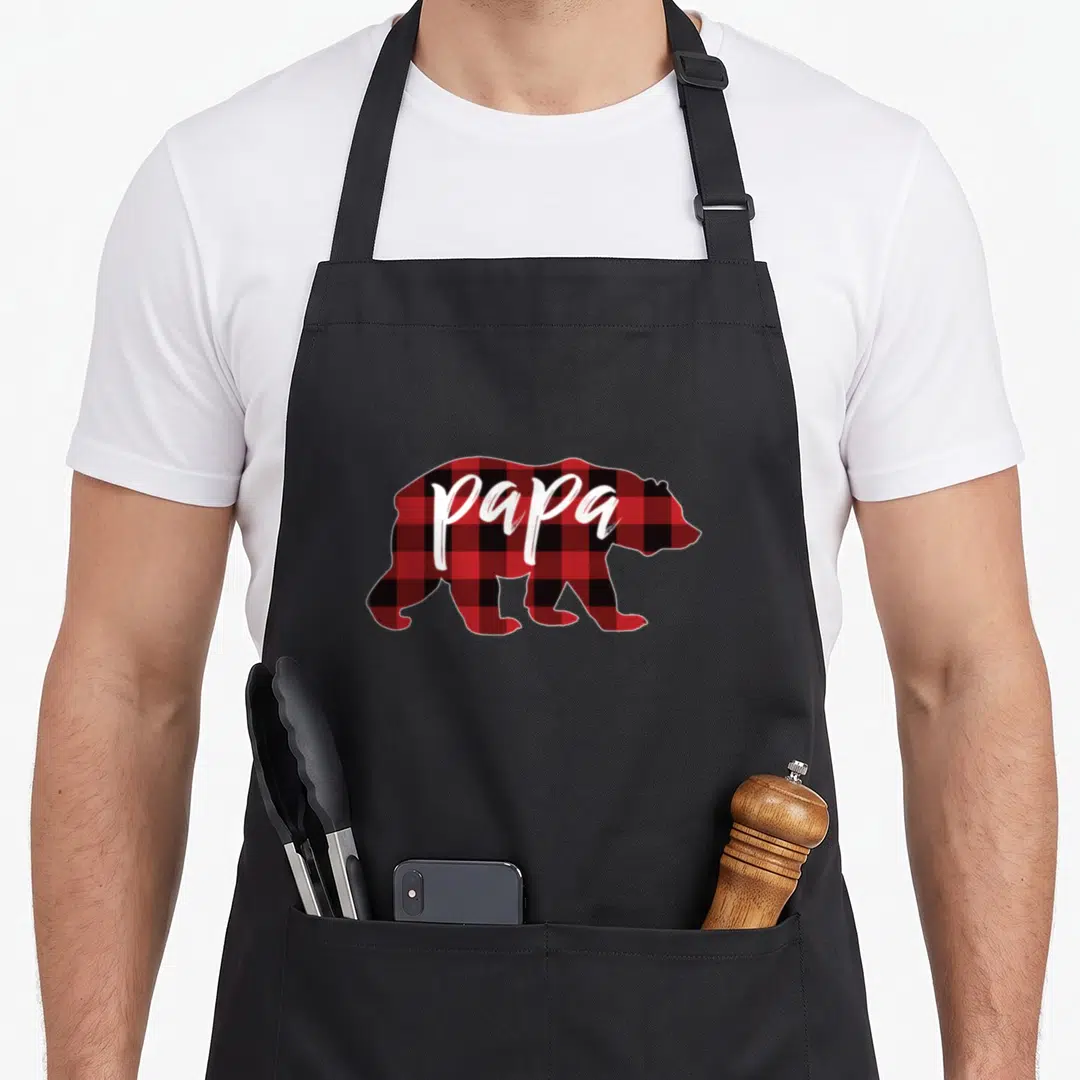 Papa buffalo apron - Red and black plaid bear silhouette with white papa text — shown on a black cotton canvas apron against a white background