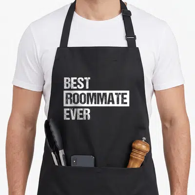 Retro roommate apron - White distressed text reading best roommate ever stacked on black background — shown on a black cotton canvas apron against a white background