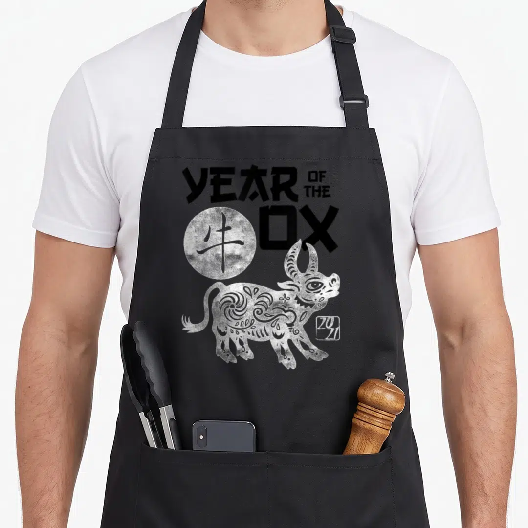 Funny chinese zodiac aprons - White ox illustration with YEAR OF THE OX text and 20 21 stamp — shown on a black cotton canvas apron against a white background