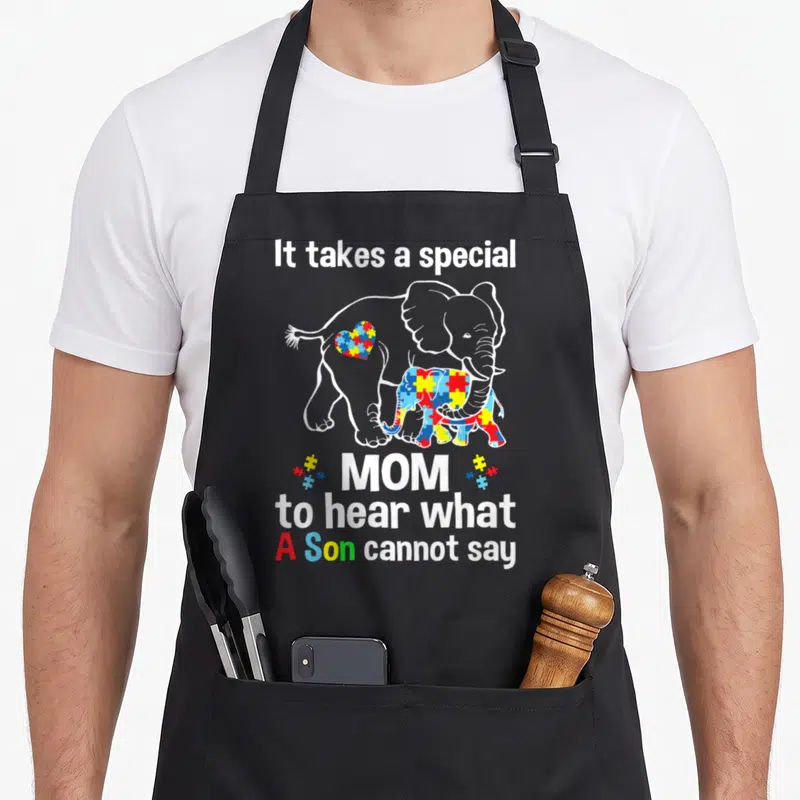 Special mom and son aprons - Elephant autism awareness apron with puzzle pattern and text about hearing what a son — shown on a black cotton canvas apron against a white background