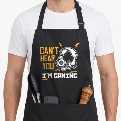 Hear gamer gaming apron - Orange and white text with cartoon headset and lightning bolts on gray background — shown on a black cotton canvas apron against a white background