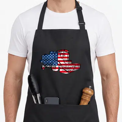 Harvester american flag apron - Cartoon combine harvester filled with red white and blue stars and stripes pattern — shown on a black cotton canvas apron against a white background