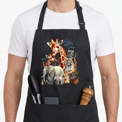 Zoo animal birthday apron - Watercolor giraffe, tiger, elephant, and raccoon cluster in orange, grey, blue, and tan — shown on a black cotton canvas apron against a white background