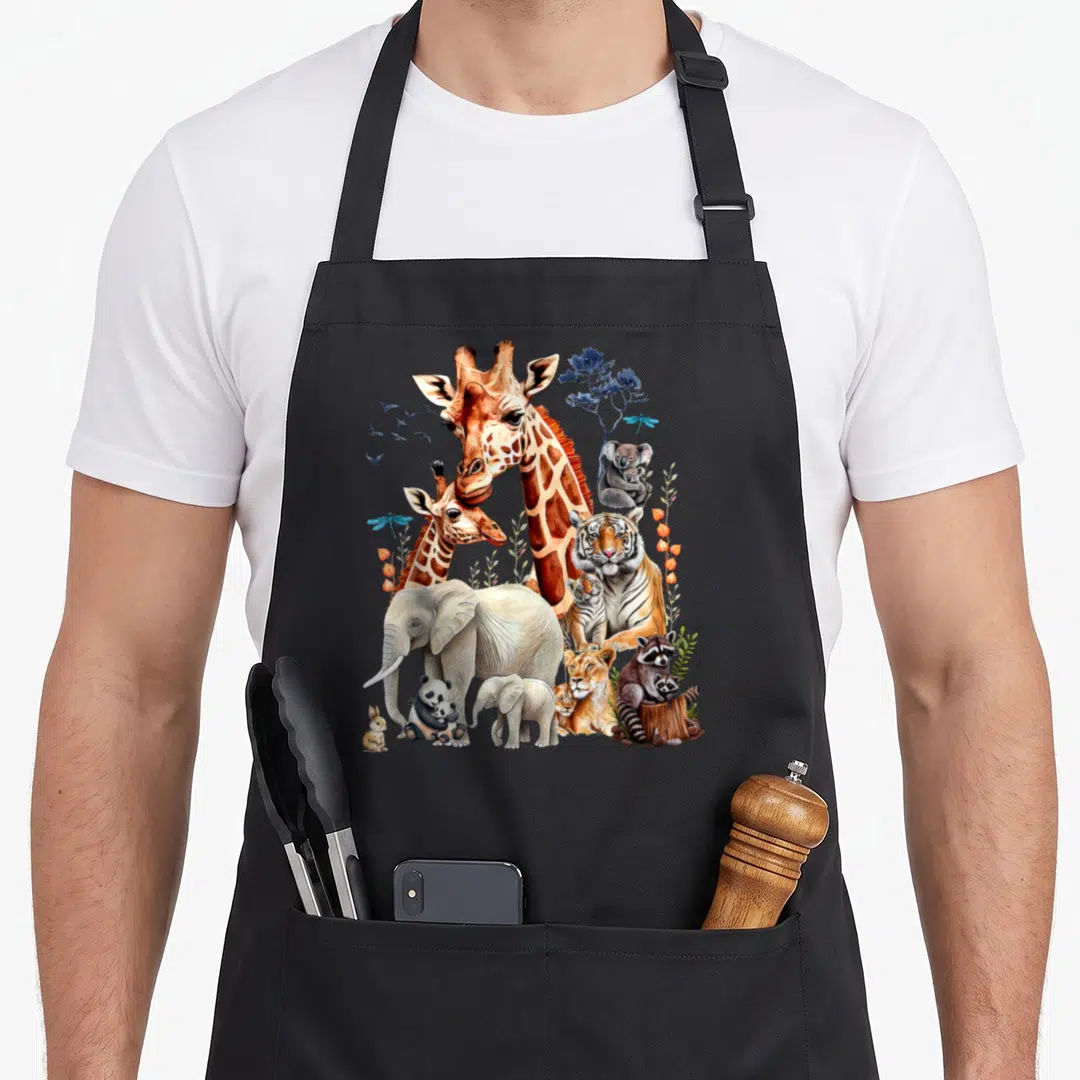 Zoo animal birthday apron - Watercolor giraffe, tiger, elephant, and raccoon cluster in orange, grey, blue, and tan — shown on a black cotton canvas apron against a white background