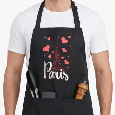 France eiffel tower paris apron - Red Eiffel Tower outline with scattered hearts and white Paris script on black fabric — shown on a black cotton canvas apron against a white background