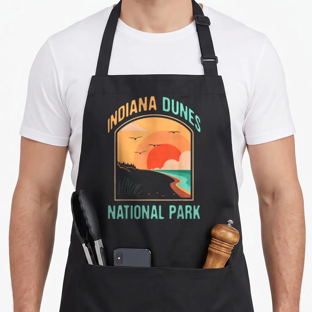 Indiana us aprons - Retro Indiana Dunes National Park sunset landscape with arched text in orange and teal — shown on a black cotton canvas apron against a white background