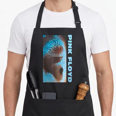 Meddle pink floyd apron - Vertical water ripple photo in blue and brown with side text PINK FLOYD — shown on a black cotton canvas apron against a white background