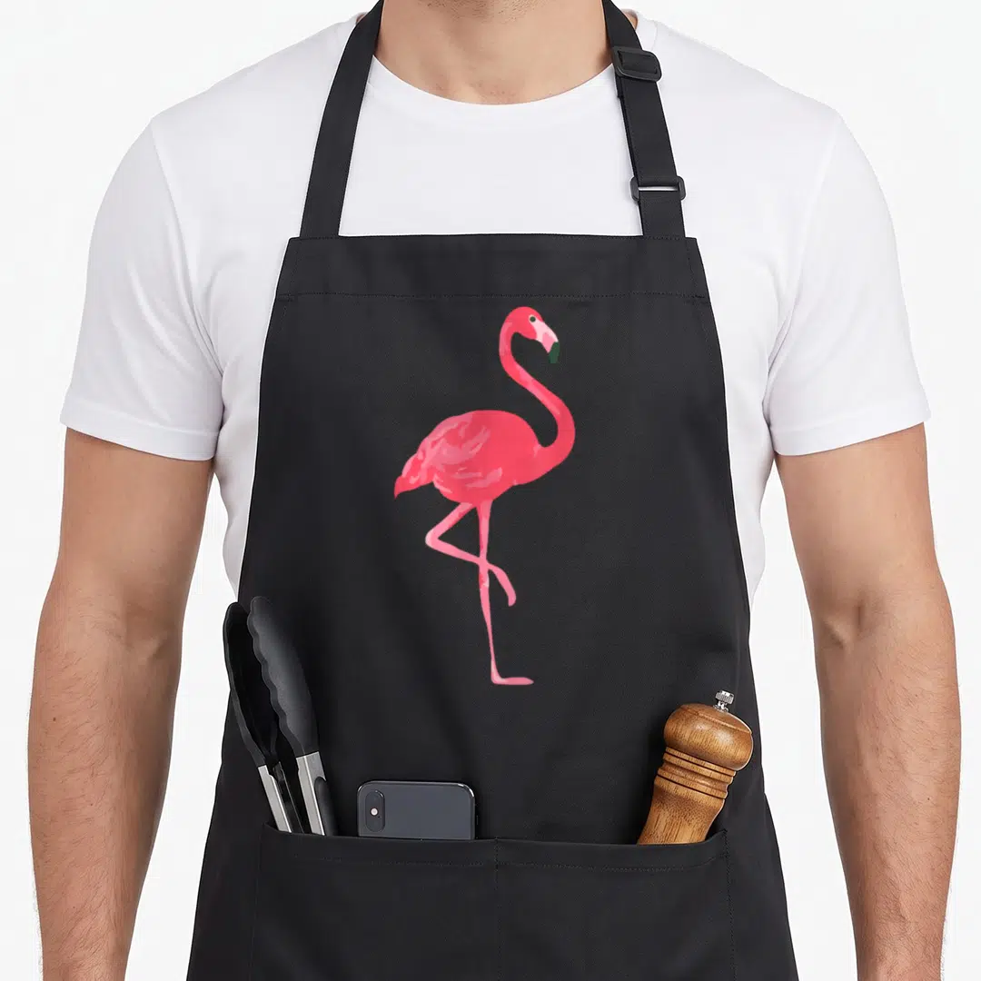 Funny pink flamingo apron - Minimalist pink flamingo standing on one leg centered on black fabric — shown on a black cotton canvas apron against a white background